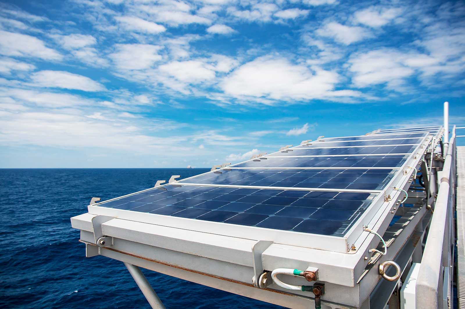 Solar panels on a ship, with the open sea in the background and a clear blue sky.