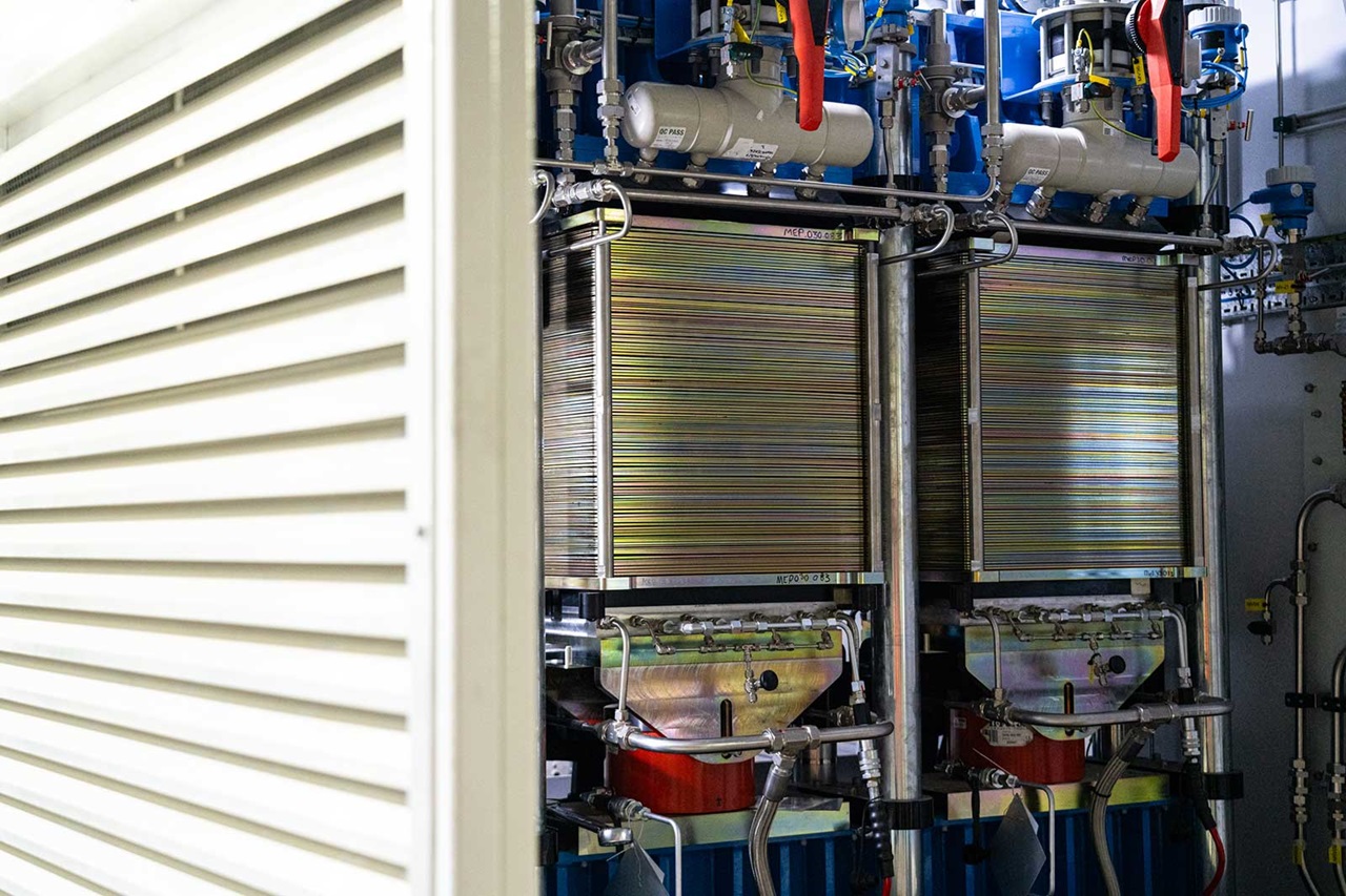 Ein Blick auf zwei große metallische Geräte in einem technischen Raum, teilweise verdeckt von einem weißen Schrank.