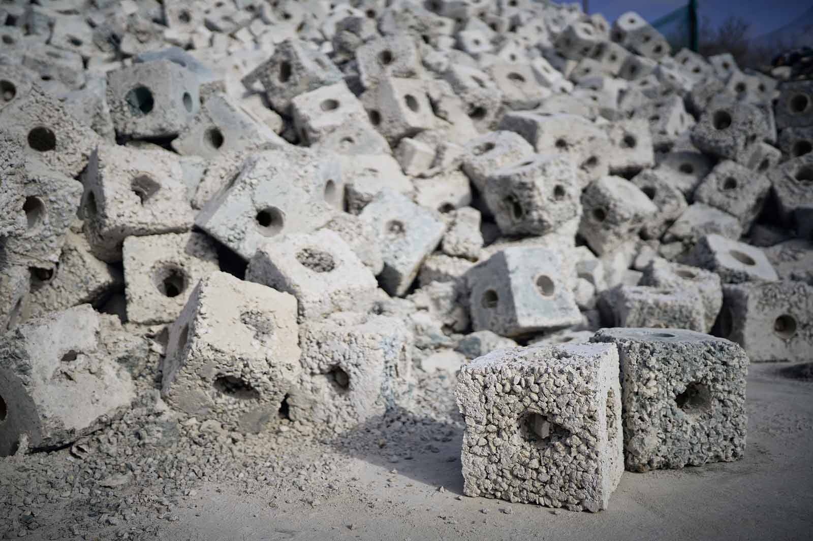 Eine Vielzahl von grauen Betonblöcken mit vertieften Löchern, die übereinander gestapelt sind.