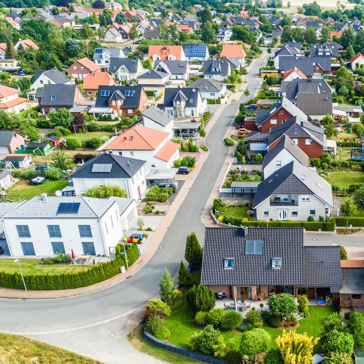 Eine Luftaufnahme eines Wohngebiets mit verschiedenen Häusern, Bäumen und einer kurvenreichen Straße.