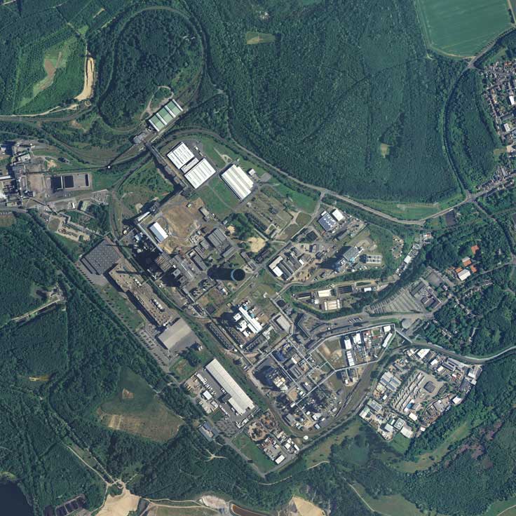 Eine Luftaufnahme eines Industriekomplexes, umgeben von Grünflächen, mit zahlreichen Gebäuden und Anlagen.