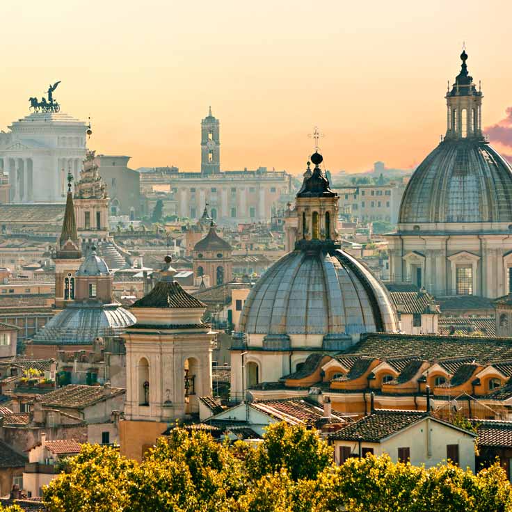 Blick auf die Dächer Roms mit historischen Gebäuden und beeindruckenden Kuppeln gegen einen goldenen Himmel.