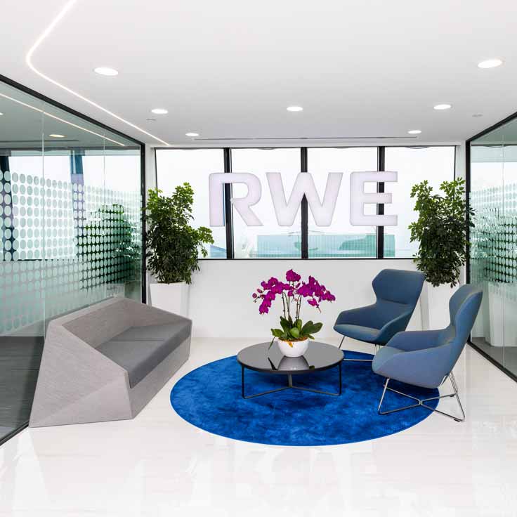 Modern office space featuring RWE logo, seating, and plants in vibrant hues.