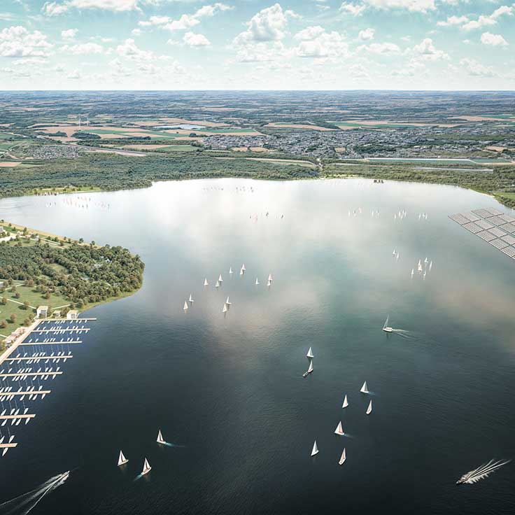 Luftaufnahme eines ruhigen Sees, der mit zahlreichen Segelbooten unter einem bewölkten Himmel übersät ist.