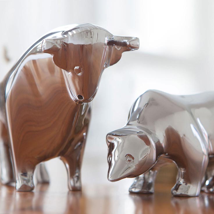 Glasfiguren eines Rinds und eines Kalbs, die auf einem Holztisch stehen, mit klaren und transparenten Oberflächen.