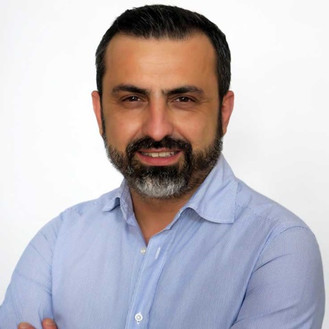 A man with crossed arms is wearing a light blue shirt against a white background. Portrait of Nello D’Orazi.