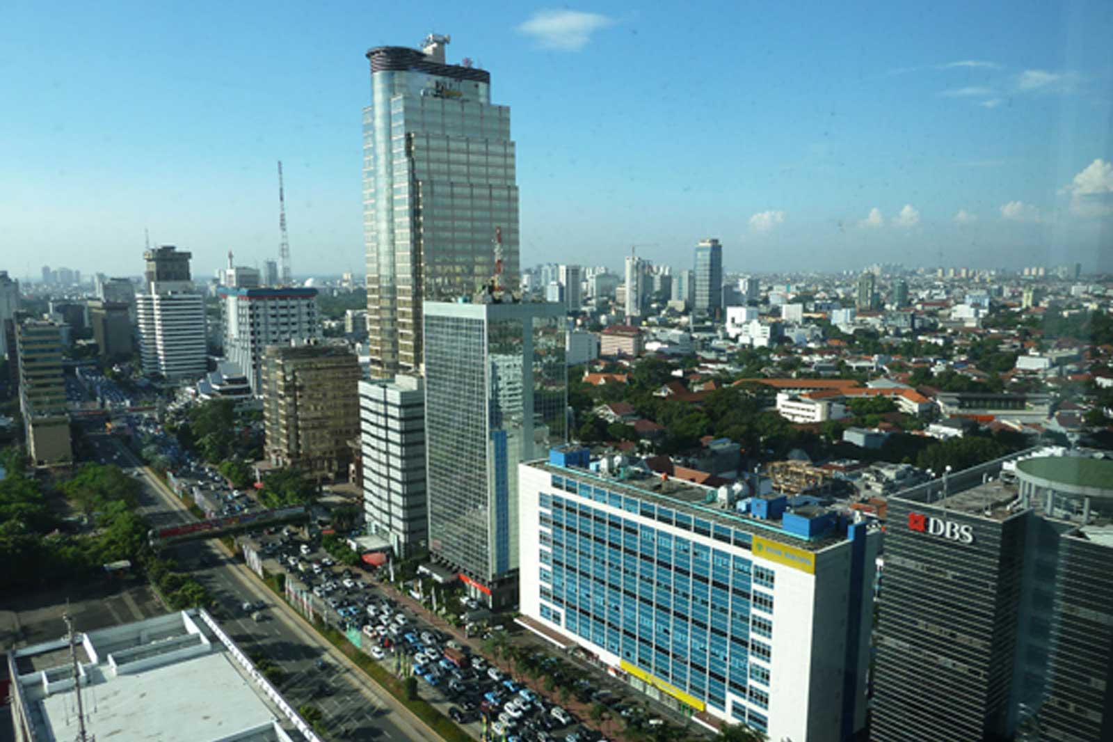 Blick auf eine moderne Stadt mit Hochhäusern und belebten Straßen unter klarem Himmel.