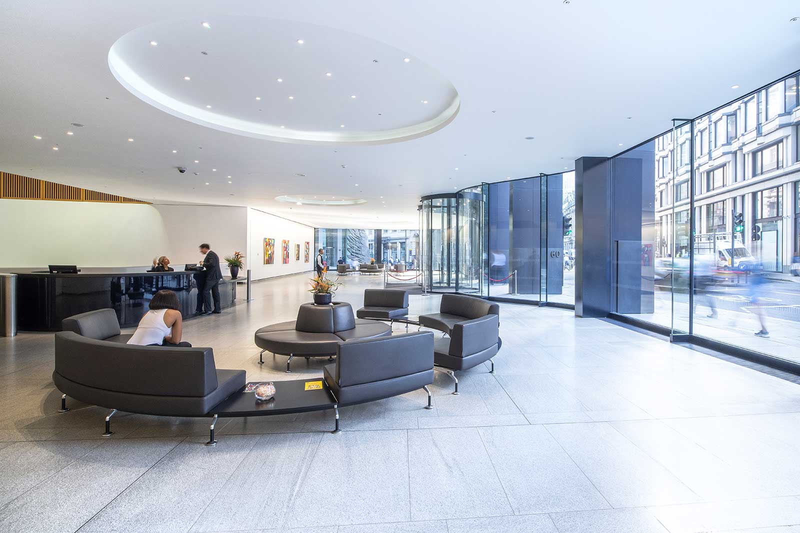 Eine moderne Empfangshalle mit eleganten Sofas, Empfangstresen und großen Fenstern, die Tageslicht hereinlassen.