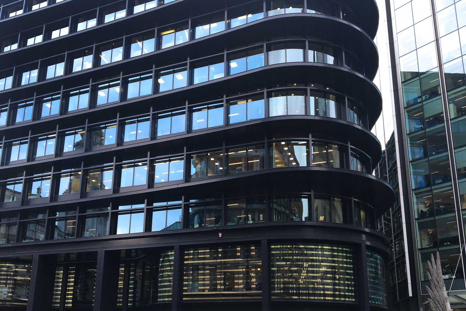 Ein moderner Bürogebäudekomplex mit gewellten Fenstern und reflektierender Glasfassade auf der rechten Seite.