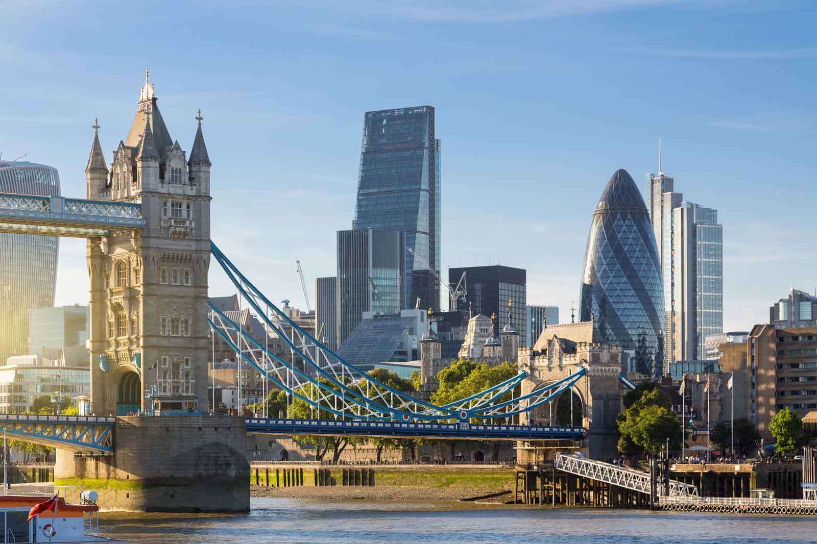 Die Tower Bridge über die Themse mit modernen Wolkenkratzern im Hintergrund an einem klaren, sonnigen Tag.