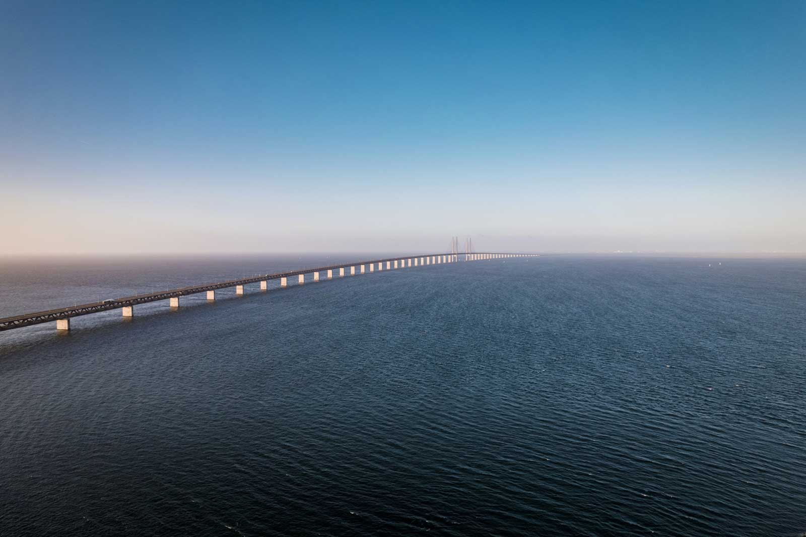 Eine weite Brücke erstreckt sich über das ruhige Wasser unter einem klaren Himmel.
