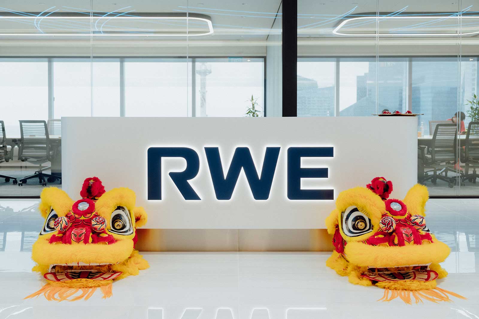 Im Büro stehen zwei gelbe Löwentänze neben dem beleuchteten Schriftzug RWE an der Empfangstheke.