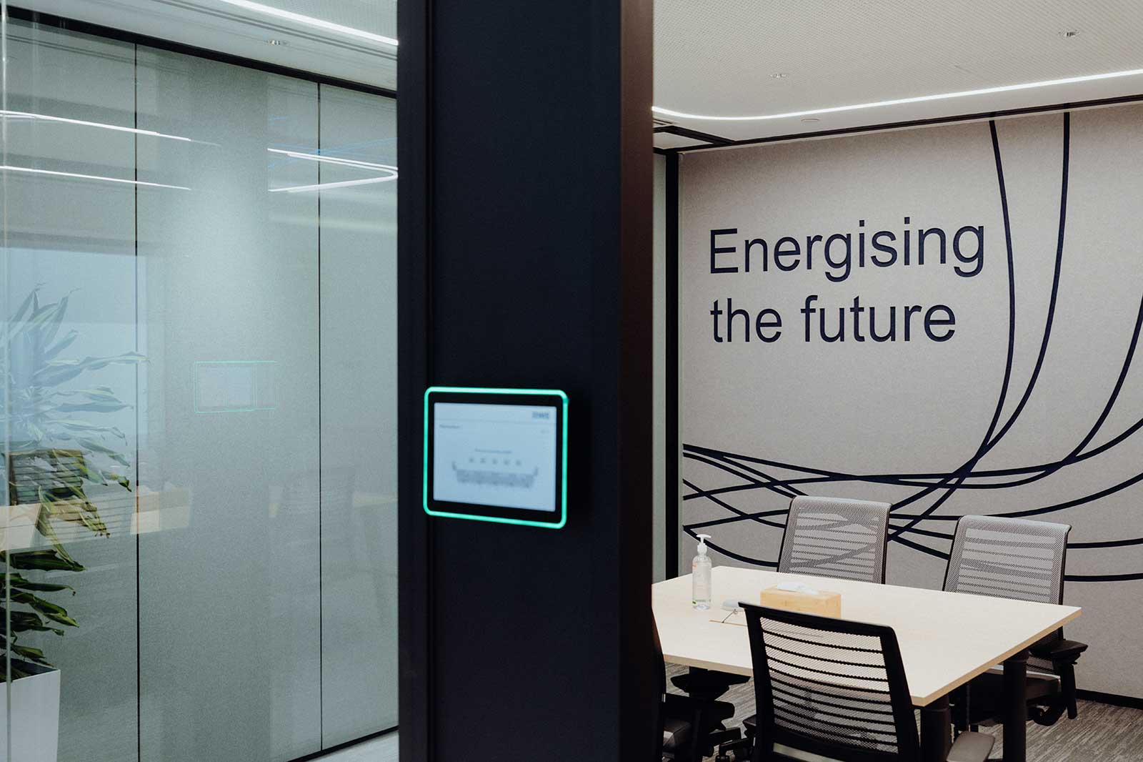 Ein modern gestalteter Meetingraum mit dem Slogan 'Energising the future' an der Wand, umgeben von eleganten Stühlen und Pflanzen.
