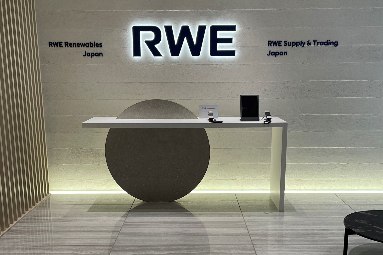 Moderne Empfangstheke mit RWE-Logo, Tablets und schlichten Designs in einem hellen Raum.