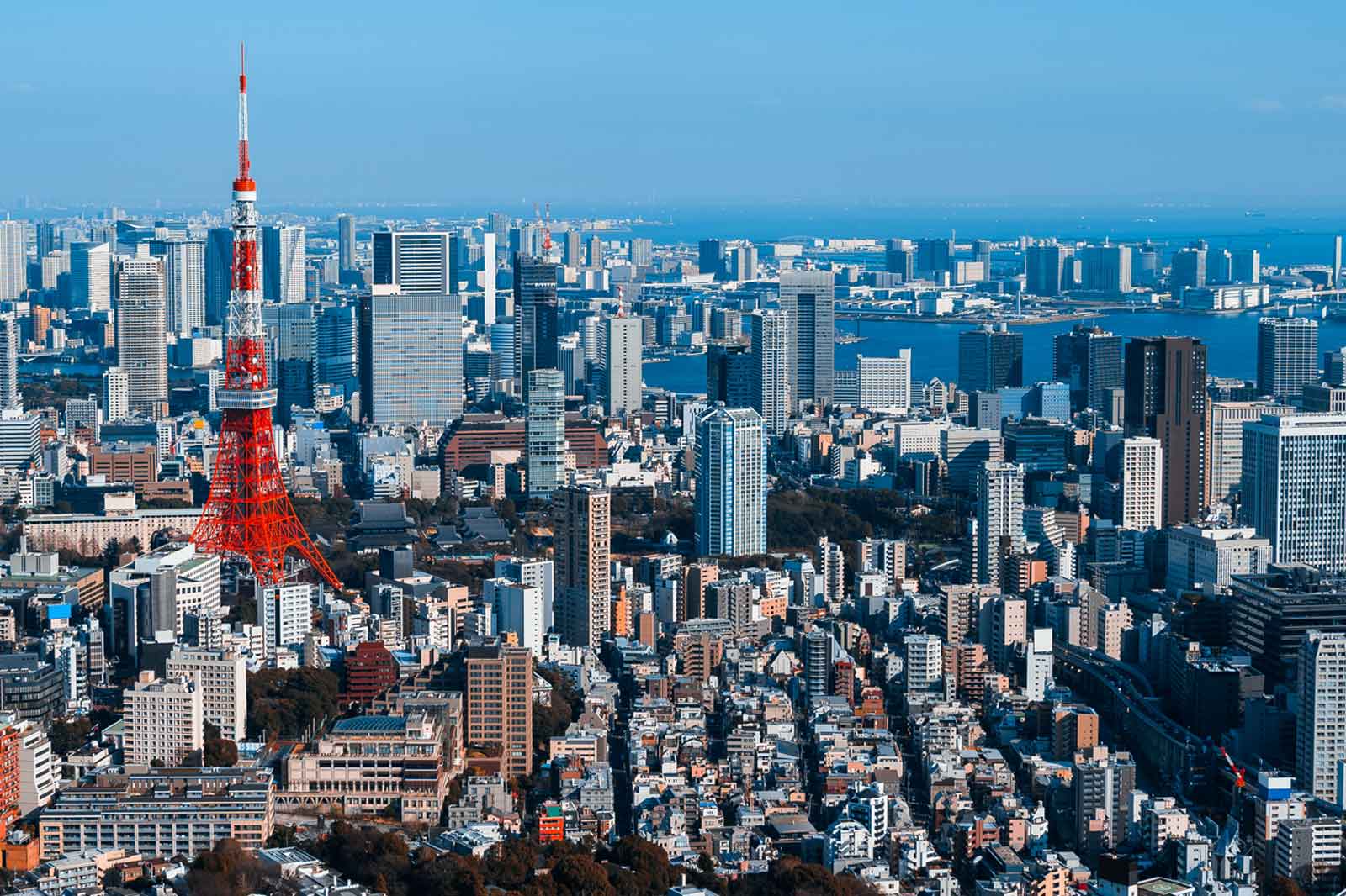 Eine Panoramaansicht von Tokio, mit dem Tokyo Tower im Vordergrund und modernen Wolkenkratzern im Hintergrund.