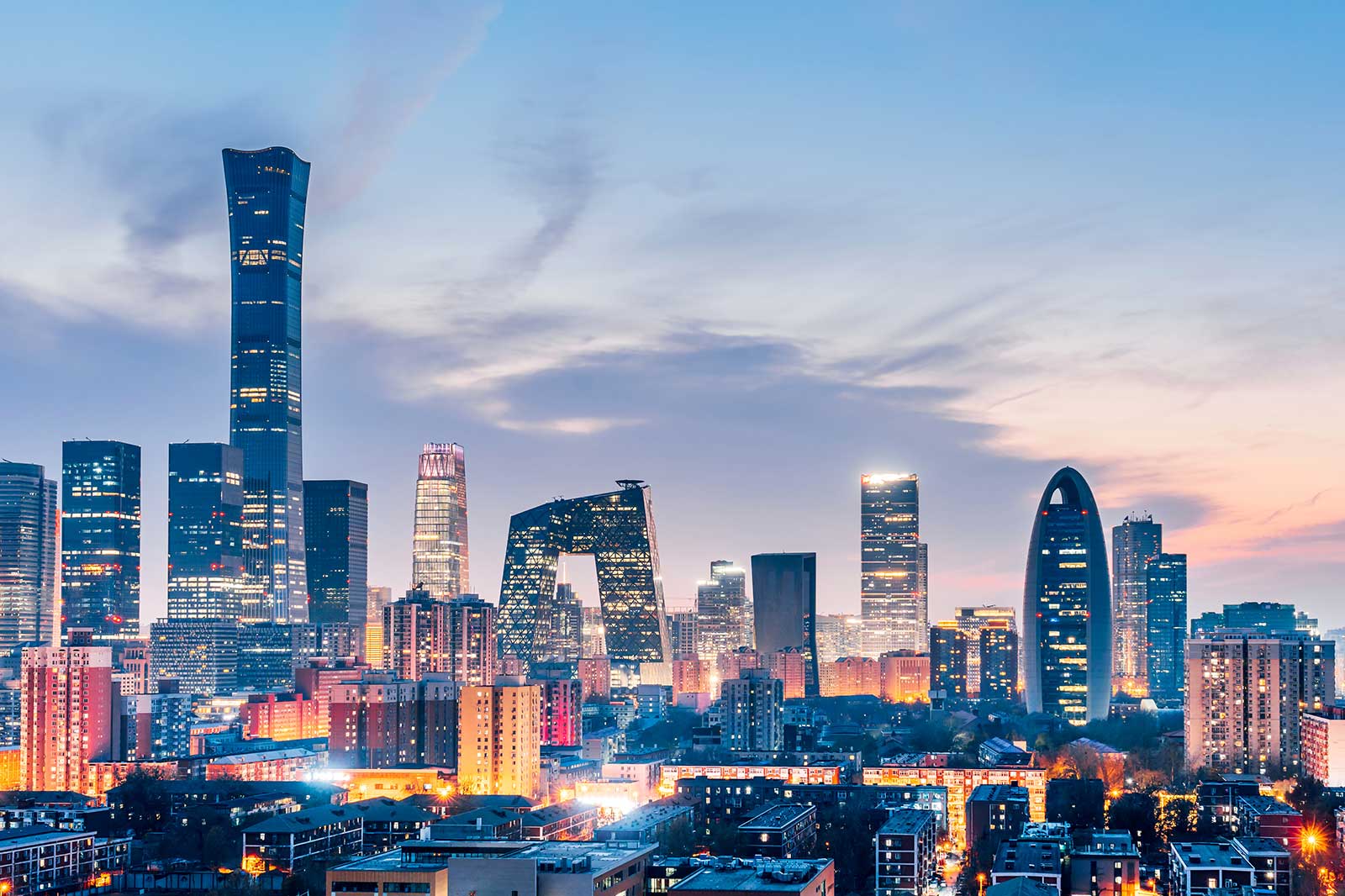 A panoramic view of Beijing's skyline at dusk, featuring iconic buildings like the China Central Television Headquarters.