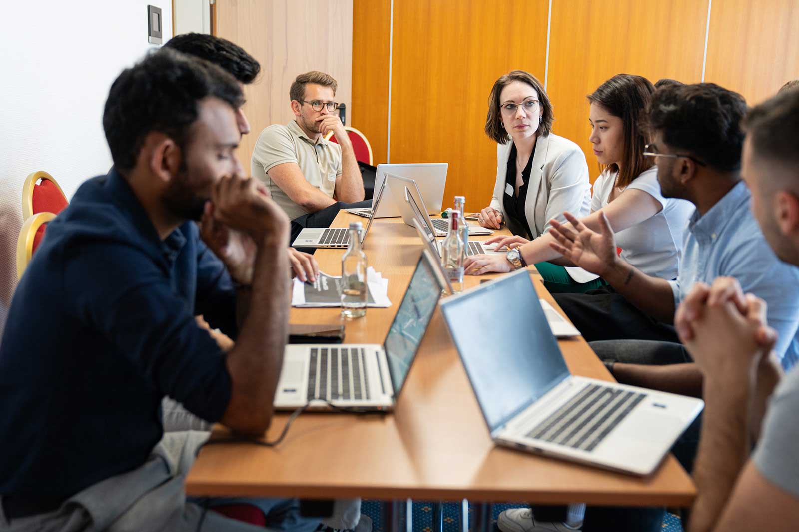 Eine Gruppensitzung in einem Konferenzraum mit Laptops und Teilnehmern, die sich angeregt unterhalten.
