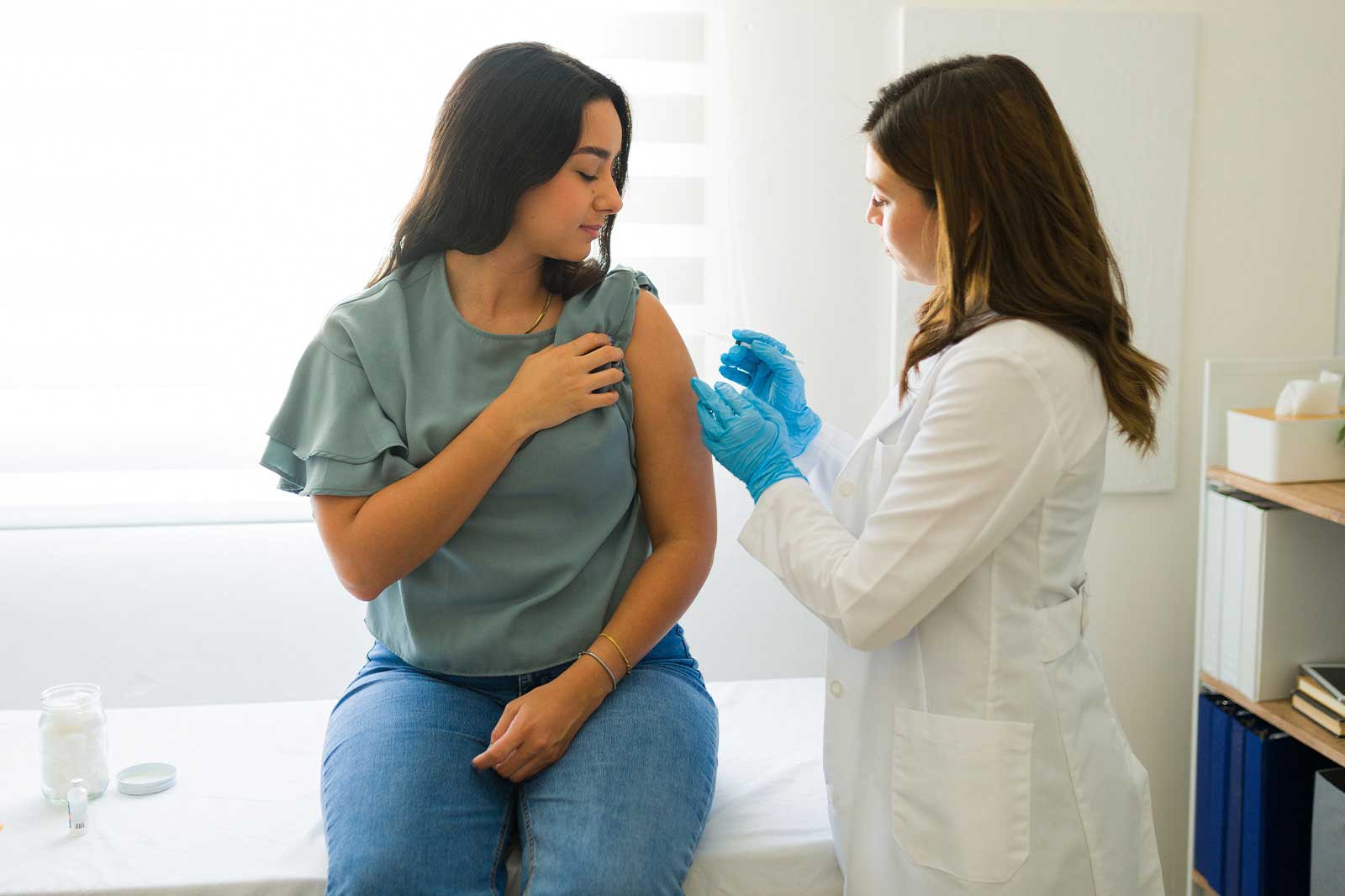 Eine Frau erhält einen Impfstoff von einer Fachkraft in einer klinischen Umgebung.