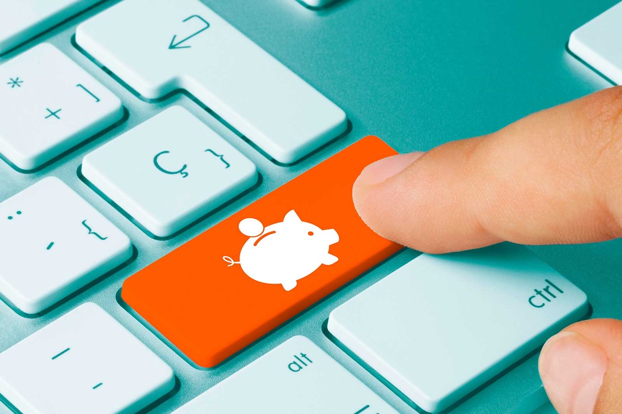 A hand presses an orange key featuring a piggy bank symbol on a light blue keyboard.