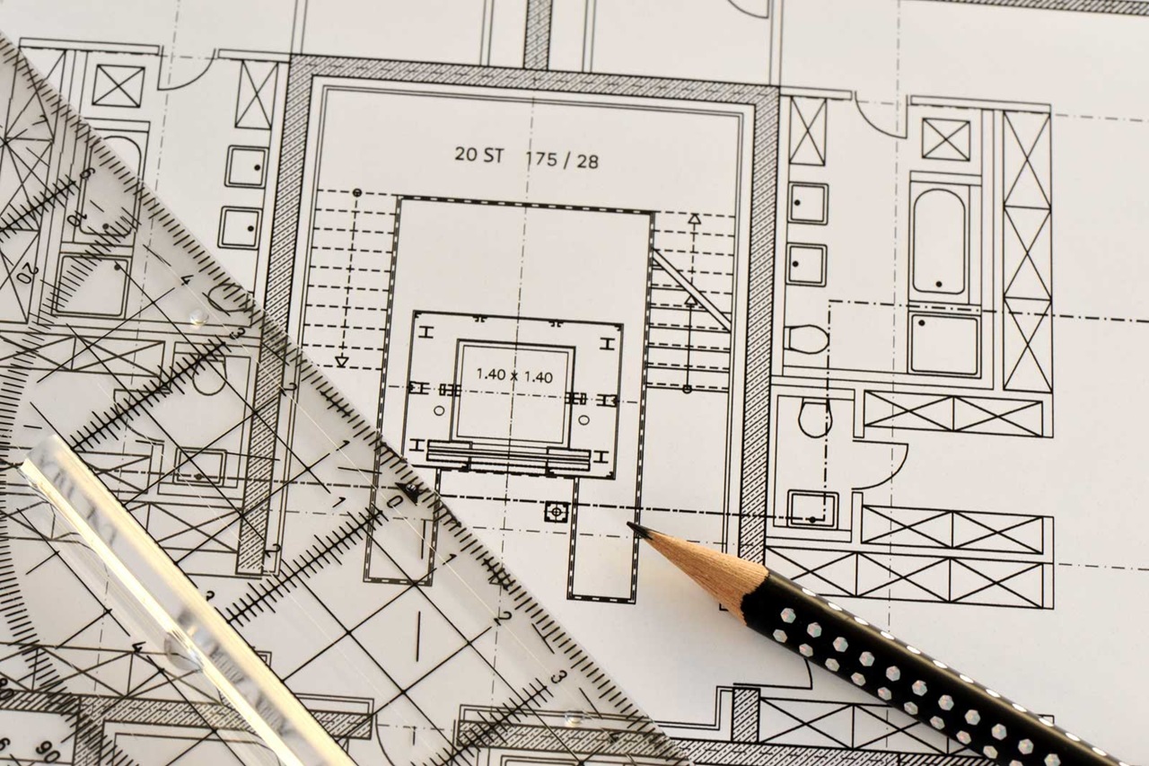 Ein detaillierter architektonischer Grundriss mit Maßen und einem Bleistift auf einer flachen Oberfläche, der Raumlayouts und Merkmale zeigt.