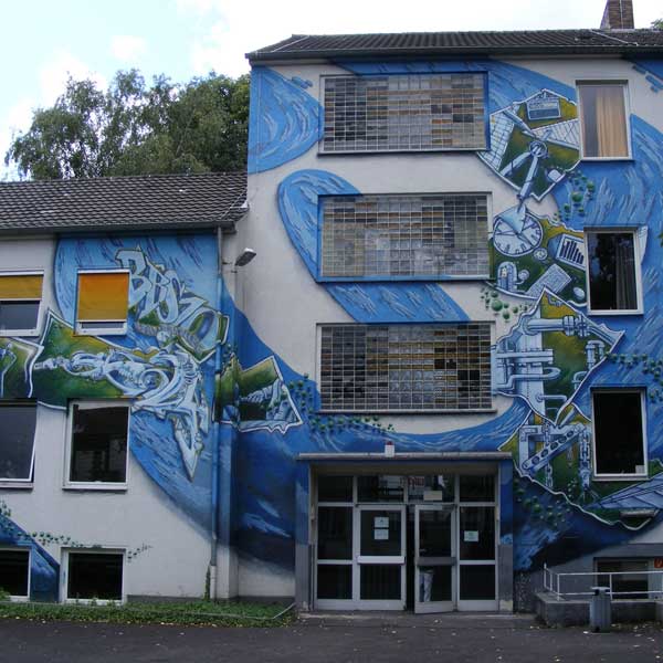 Ein Gebäude mit einem großen Wandgemälde, das blaue Wellen und abstrakte Designs zeigt, die künstlerischen Ausdruck auf seiner Fassade betonen.