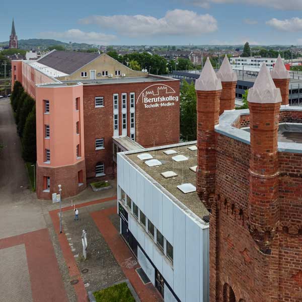 Eine Luftaufnahme einer Stadtlandschaft mit einem Kollegegebäude und einer historischen Struktur mit Türmen.
