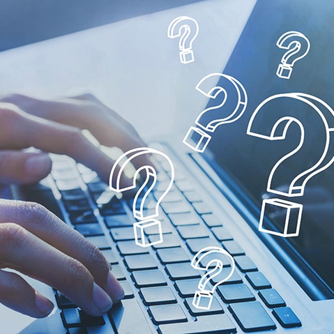 Eine Person tippt auf der Tastatur eines Laptops mit mehreren umreißenden Fragezeichen, die darüber schweben.