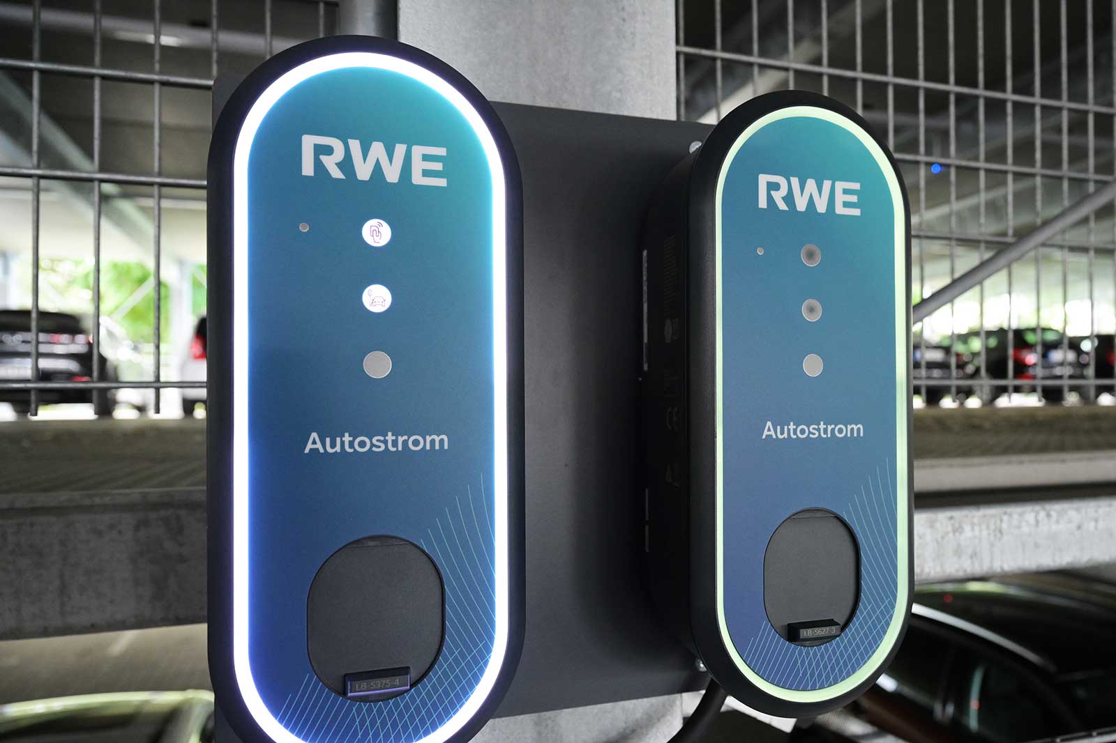 Zwei RWE Autostrom-Elektroautoladegeräte an einer Wand in einem Parkhaus, mit Anzeigeleuchten und ansprechendem Design.