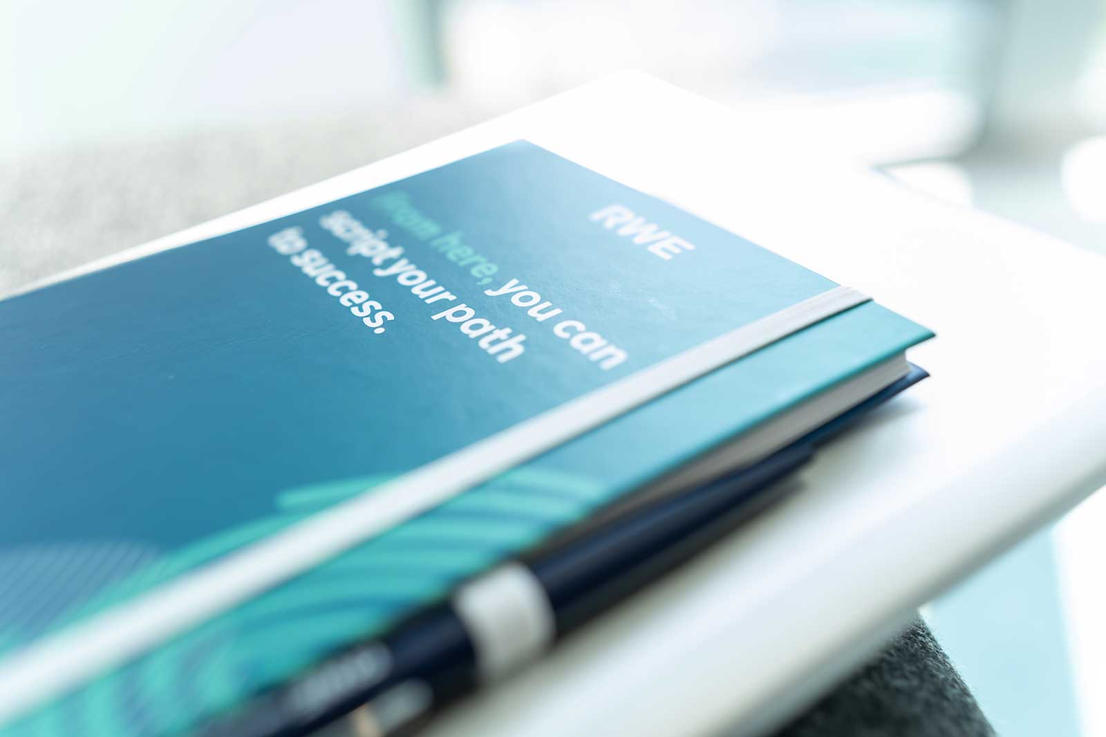 Eine Nahaufnahme eines Notizbuchs und eines Stifts, mit dem Text: 'Von hier aus können Sie Ihren Weg zum Erfolg einfach gestalten.