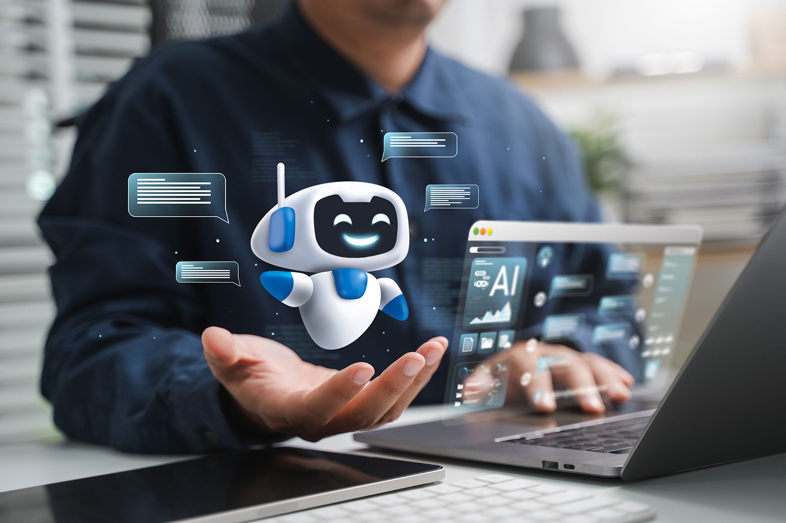 Ein weiß-blauer cartoonartiger Roboter-Hologramm schwebt über einer offenen Hand über einem Schreibtisch mit Laptop und Tastatur, dazu durchscheinende Sprechblasen und ein Bildschirm mit „AI“.