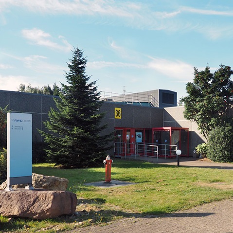 Ein modernes Gebäude mit der Nummer 36, umgeben von Grünflächen und einem Hydranten.