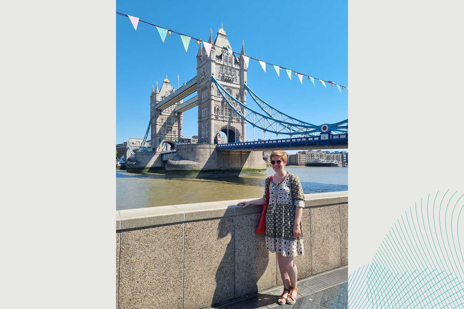 Eine Person steht am Fluss, während die Tower Bridge im Hintergrund mit bunten Fähnchen geschmückt ist.