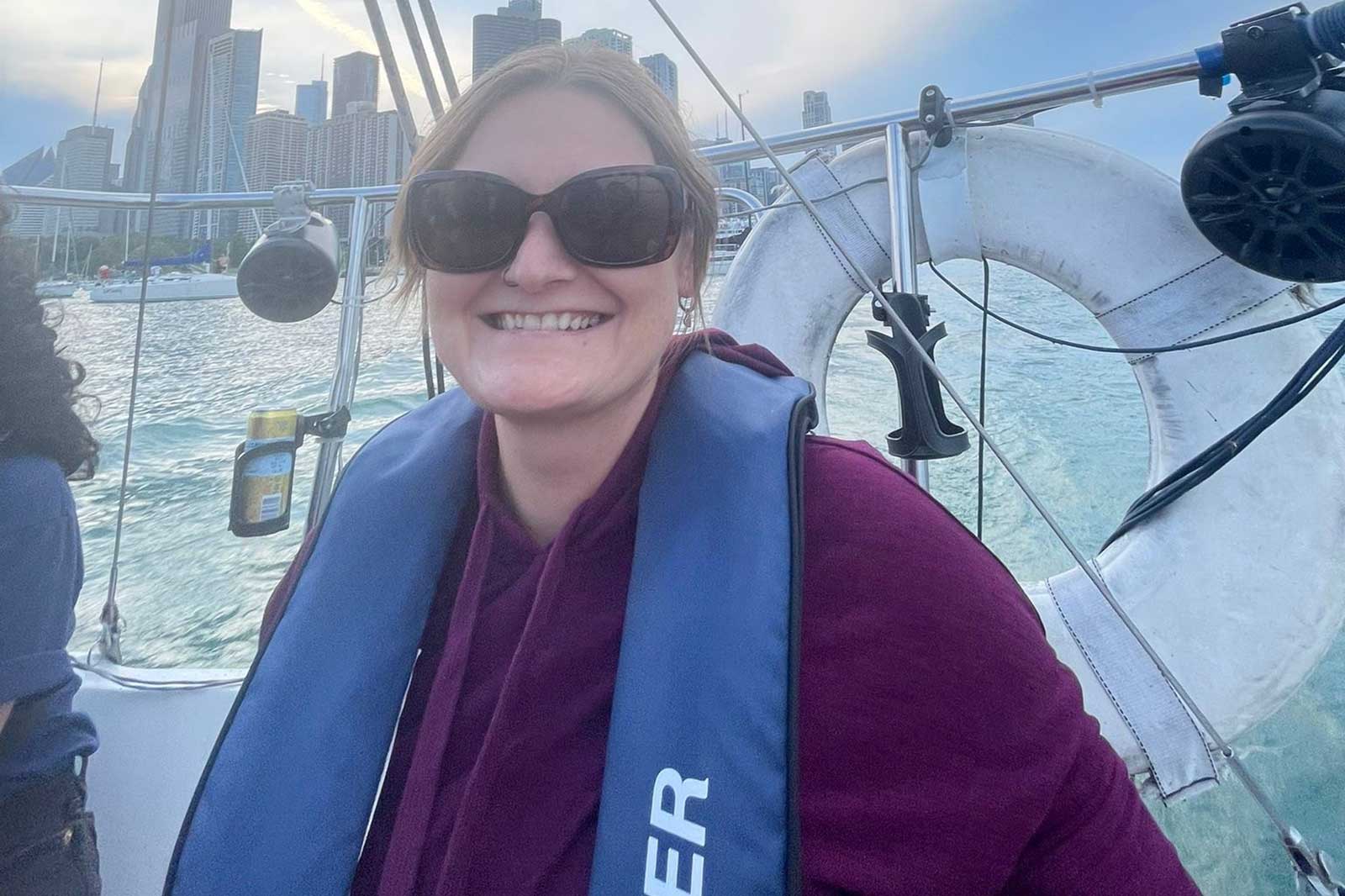 Eine Person auf einem Boot mit Hochhäusern im Hintergrund. Das Wasser glänzt im Sonnenlicht.