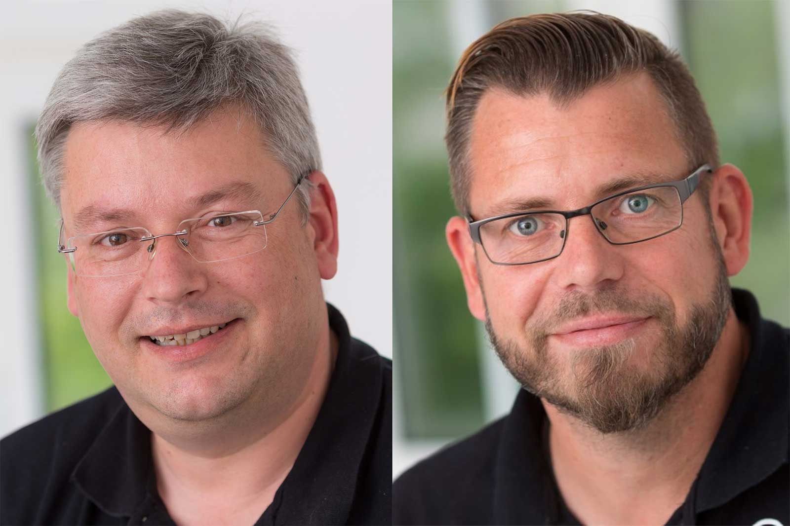 Zwei Männer mit grauem und dunkelblondem Haar, beide tragen schwarze T-Shirts, vor einem unscharfen Hintergrund.