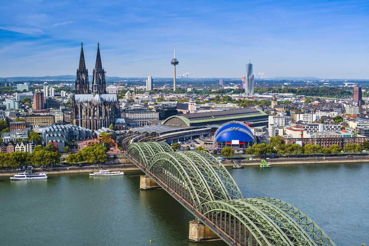 Kölner Skyline mit dem Kölner Dom und der Hohenzollernbrücke über dem Rhein an einem sonnigen Tag.