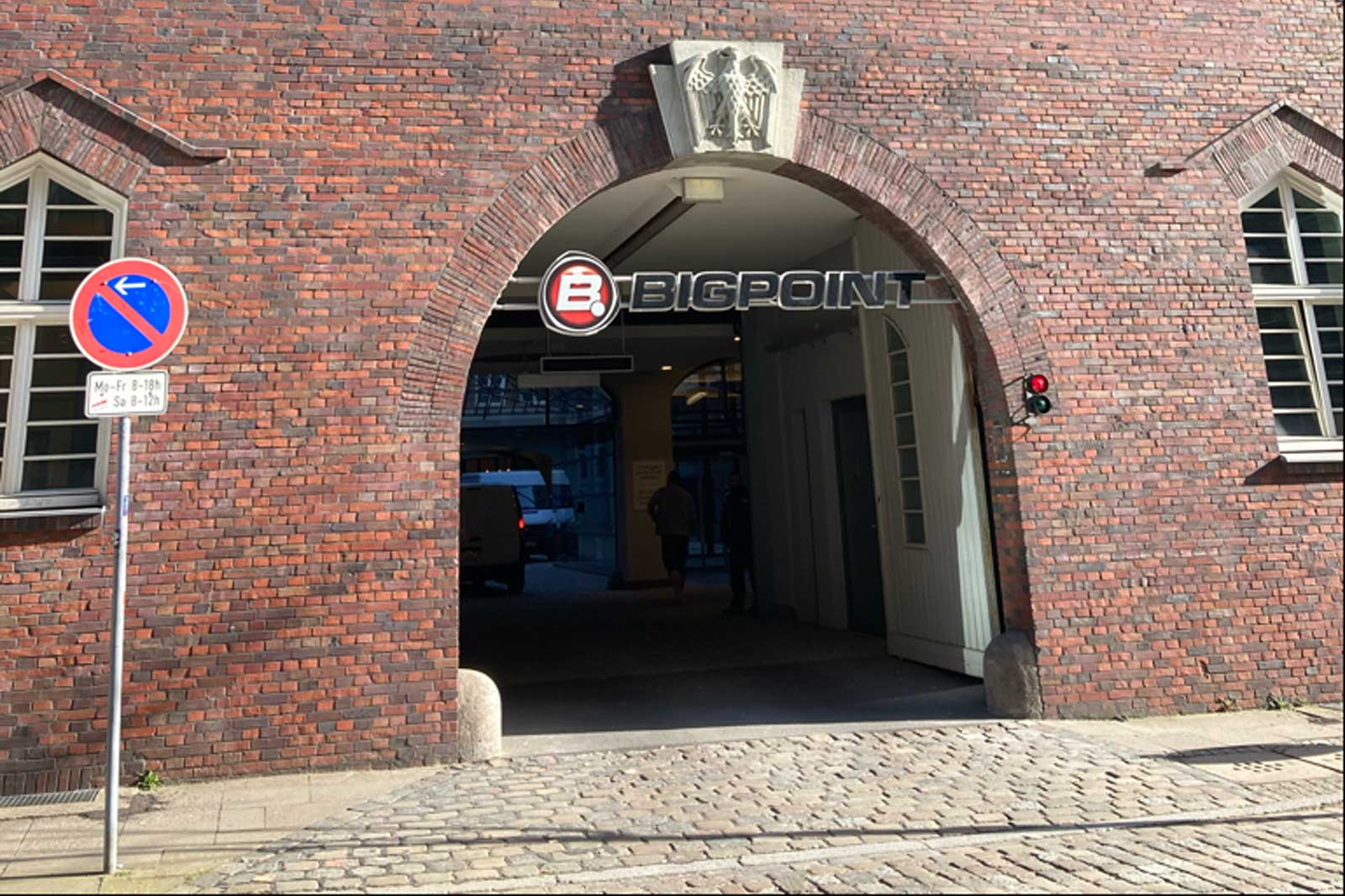 A brick archway featuring the sign 'BIGPOINT'. Traffic signs are visible, along with a red light at the entrance.