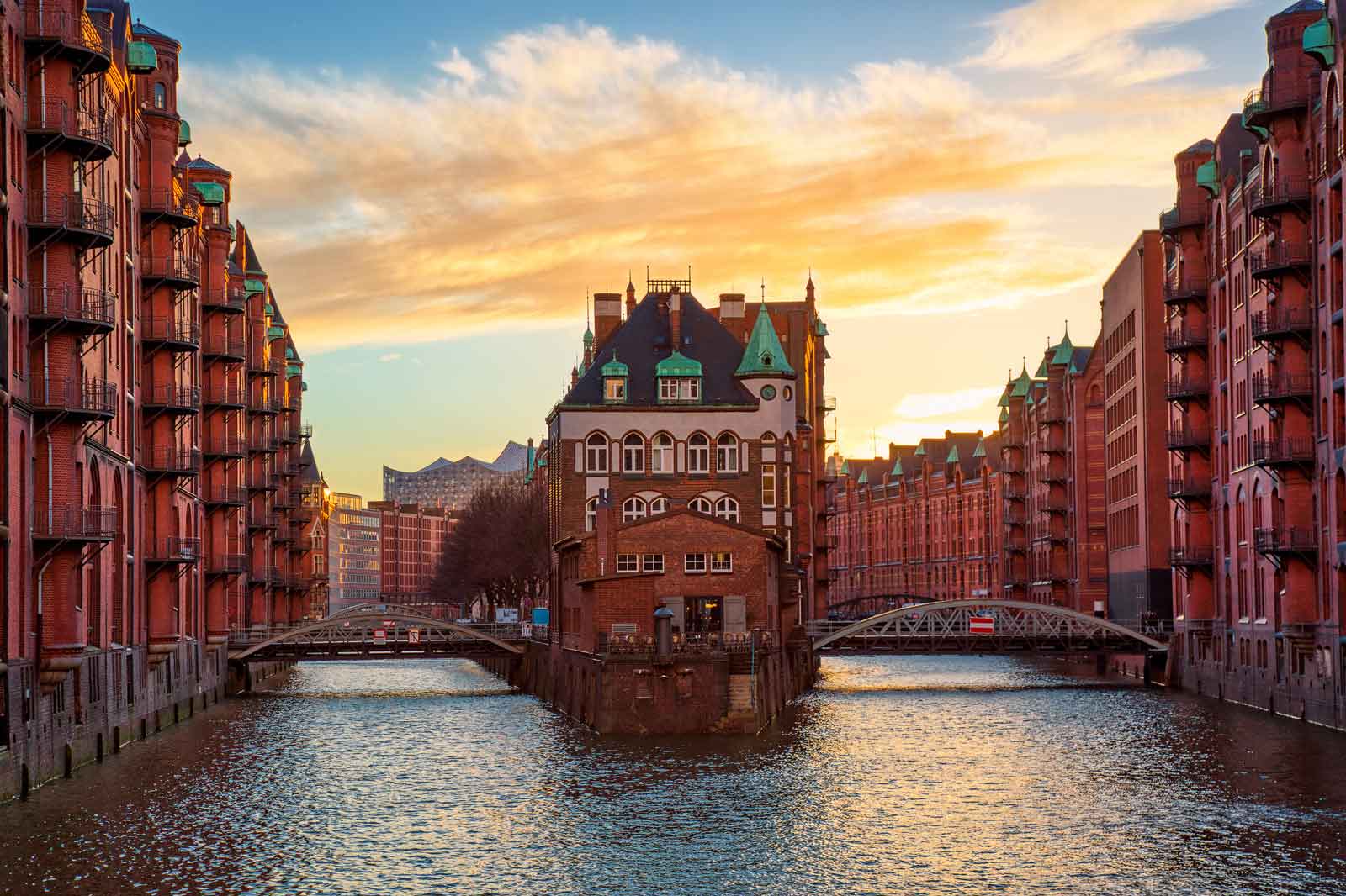 A beautiful sunset over the historic warehouses in Hamburg, featuring an old building in the centre.