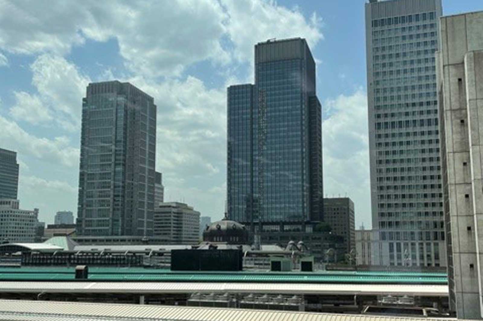 View of modern skyscrapers under a cloudy sky, with a train station in the foreground.